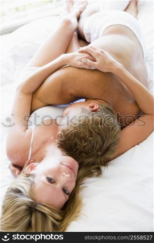 Couple lying in bed embracing and smiling