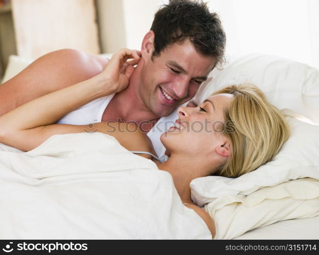 Couple lying in bed smiling