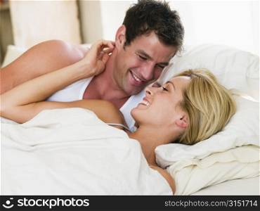 Couple lying in bed smiling
