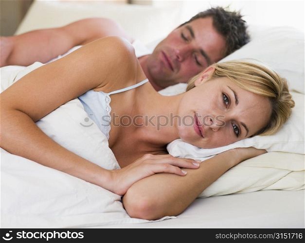 Couple lying in bed with the man sleeping