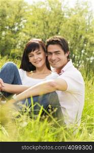 Couple lying in grass, smiling and hugging