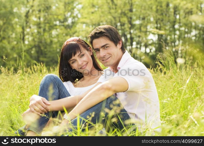 Couple lying in grass, smiling and hugging