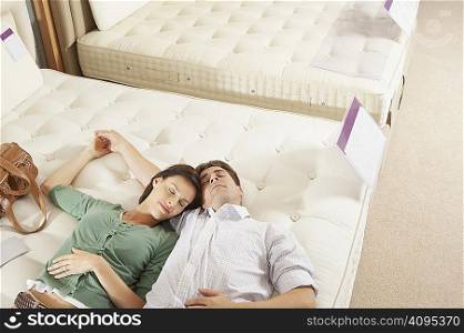 Couple lying on bed in furniture store