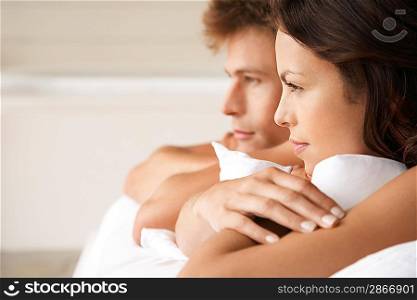Couple lying on stomachs in bed head and shoulders profile