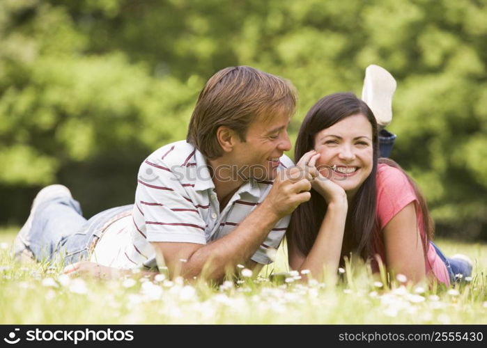 Couple lying outdoors with flower smiling