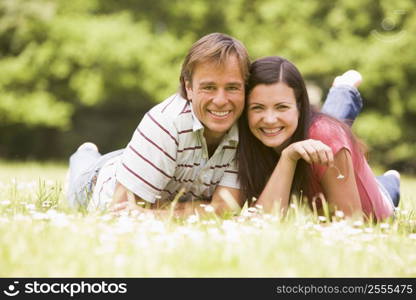 Couple lying outdoors with flower smiling