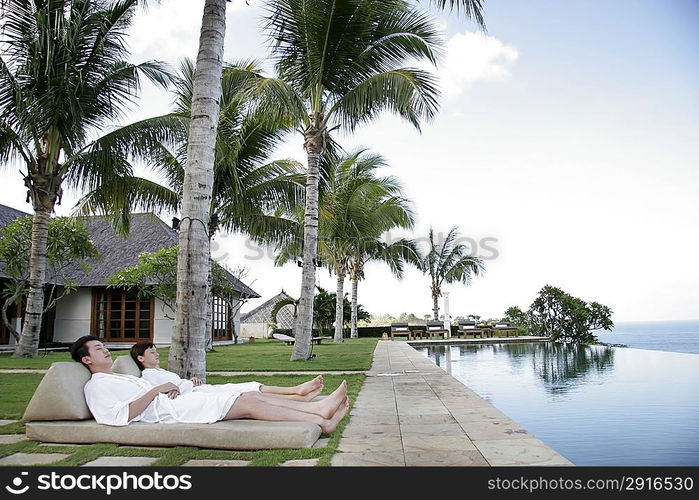 Couple lying together on Chaise Longue outdoors