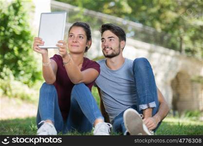 couple makes a selfie for tablet in a park