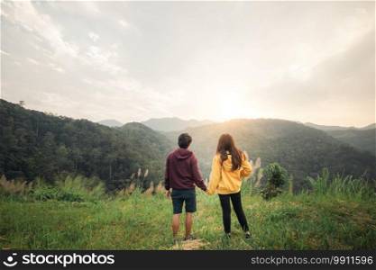 couple making heart shape with hands and enjoy the sunset view on mountain peak at Mae Wong national park Thailand.
