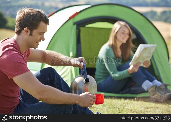 Couple Making Hot Drink Whilst Camping In Countryside