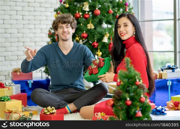 Couple man and woman as lovers enjoy Christmas festival to stay at home with Christmas tree and several decoration, they also look at camera and they look happy with this moment.