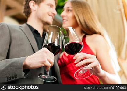 Couple, man and woman, at winetasting in a restaurant, each with glass of red wine in hand