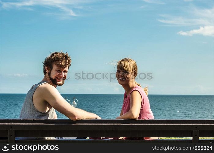 Couple man and woman dating by sea ocean outdoor. Young girl and guy sitting on bench. Summer love.. Couple man and woman dating outdoor.