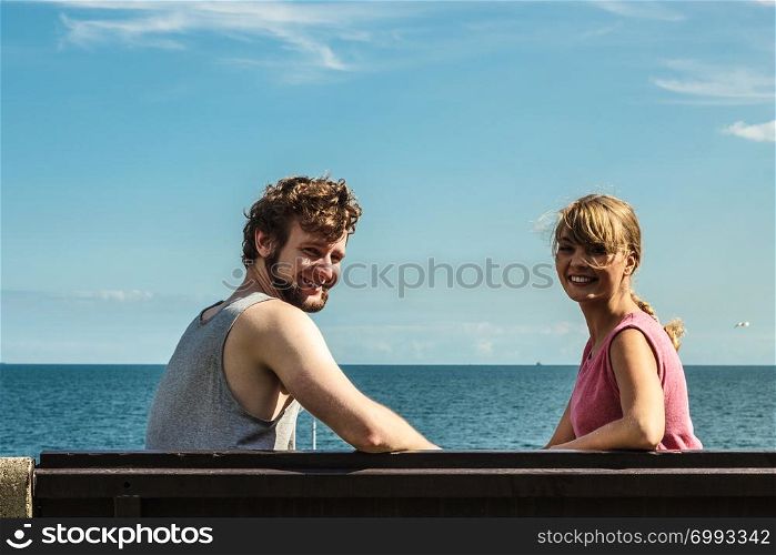 Couple man and woman dating by sea ocean outdoor. Young girl and guy sitting on bench. Summer love.. Couple man and woman dating outdoor.