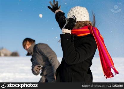 Couple - man and woman - having a winter walk and having a snowball fight