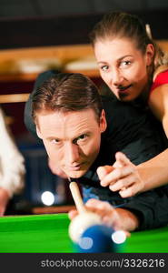 Couple (man and woman) in a billiard hall playing snooker