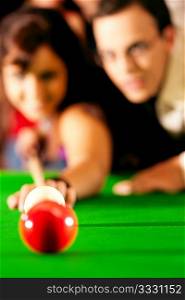 Couple (man and woman) in a billiard hall playing snooker