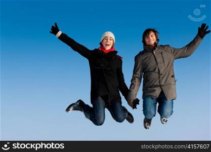 Couple - man and woman - jumping high on a winter day