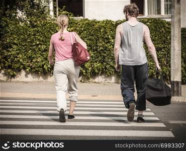 Couple man and woman with sport gym bags crossing pedestrian crosswalk outdoor. Active young girl and guy in training suit sportswear.. Couple man and woman with sport bags.