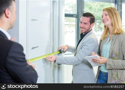 Couple measuring a door, salesman helping