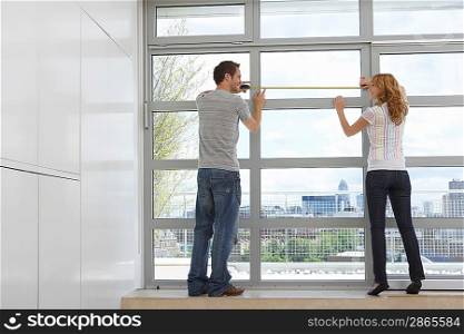 Couple Measuring Windows in New Apartment