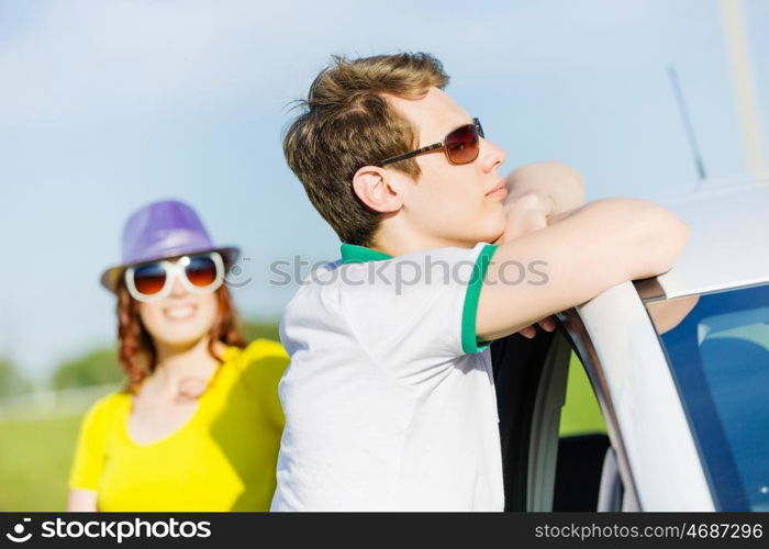 Couple near car. Young people sitting near car aside of road