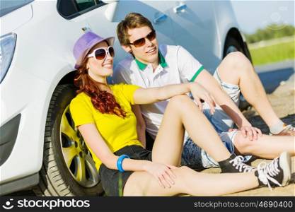 Couple near car. Young people sitting near car aside of road