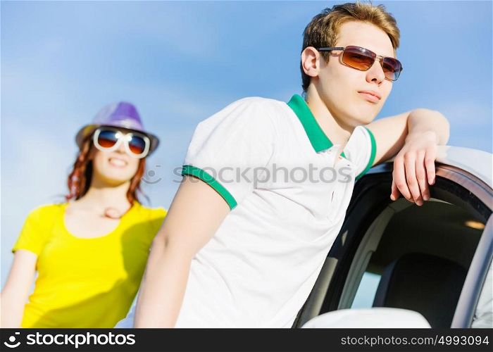 Couple near car. Young people sitting near car aside of road