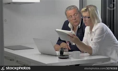 Couple of adults looking at tablet and talking in kitchen