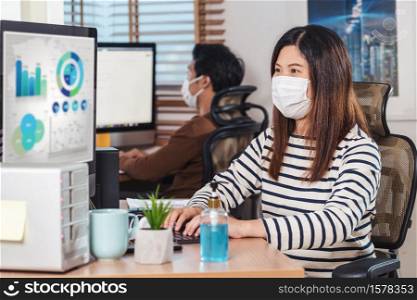 Couple of Asian colleagues wearing the surgical mask and working with computer in Home office when Covid-19 pandemic, Coronavirus outbreak,education and Social distancing,new normal concept