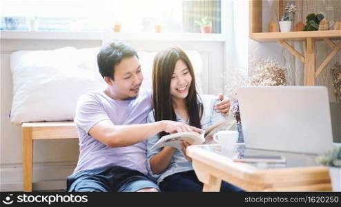 Couple of Asian Lover sitting together and reading book in the morning with warm feeling at modern co-working space, Lifestyle and leisure with love concept