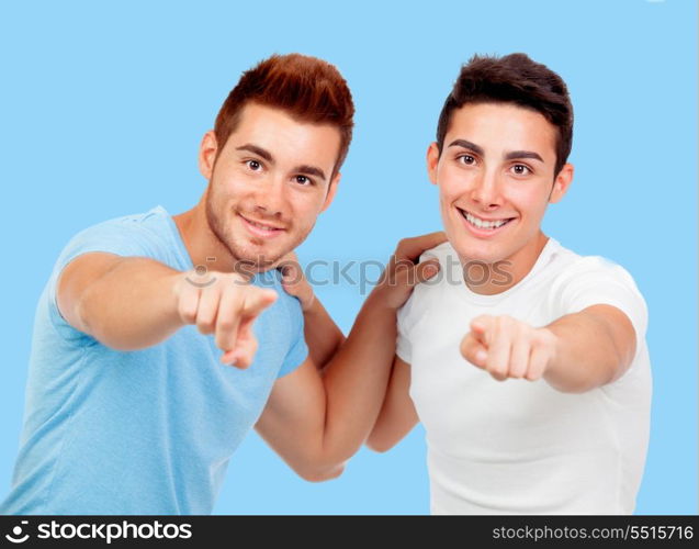 Couple of best friends pointing to the camera on a blue background