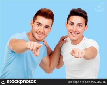 Couple of best friends pointing to the camera on a blue background