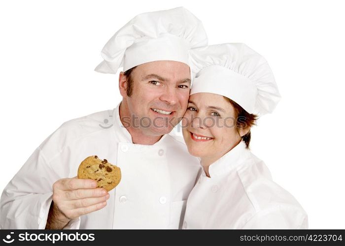 Couple of chefs smiling and enjoying a cookie. Isolated on white.