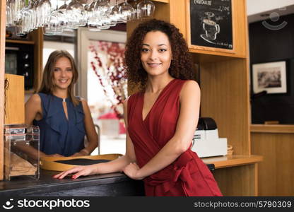 Couple of female baristas standing inside their coffee house