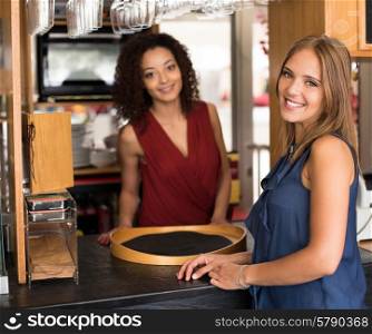 Couple of female baristas standing inside their coffee house