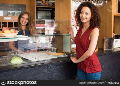 Couple of female baristas standing inside their coffee house
