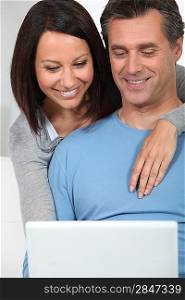 couple of fortysomethings looking happy with computer