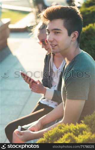 Couple of friends, teenage girl and boy, having fun together, sitting in center of town, spending time together