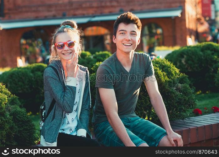 Couple of friends, teenage girl and boy, having fun together, sitting in center of town, spending time together