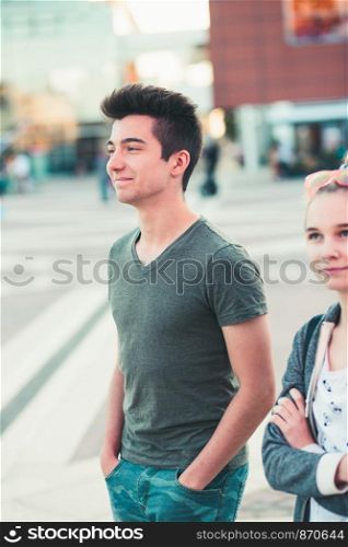 Couple of friends, teenage girl and boy, having fun together, walking in center of town, spending time together