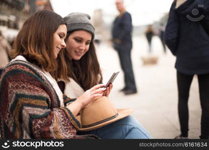 Couple of friends with a smartphone in the city street