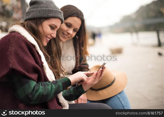 Couple of friends with a smartphone in the city street