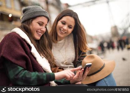 Couple of friends with a smartphone in the city street