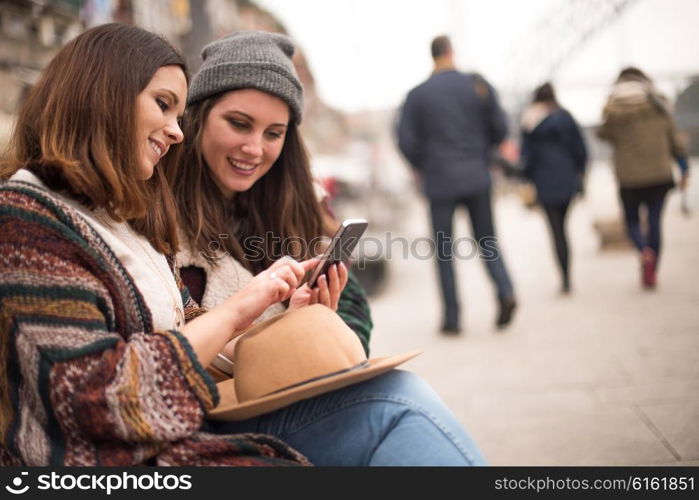 Couple of friends with a smartphone in the city street