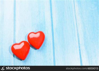 Couple of glossy red hearts for Valentine's day on blue wooden table