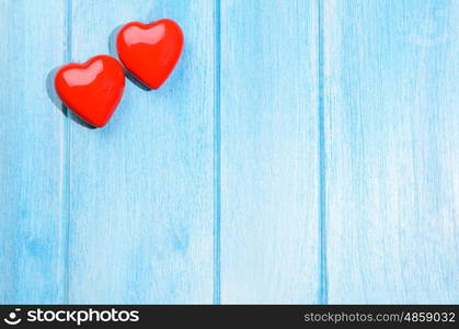 Couple of glossy red hearts for Valentine's day on blue wooden table