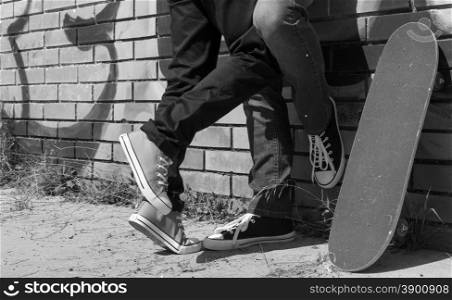 Couple of guys with his skateboard next to a wall with graffiti