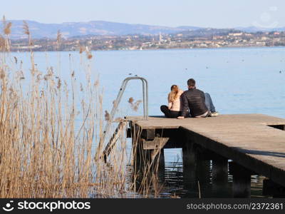 couple of kids sitting on the jetty by the lake. couple of kids sitting on the jetty by the lake-