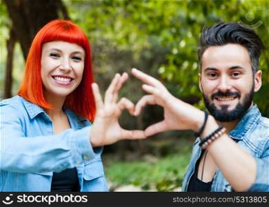 Couple of lovers forming a heart with their hands in a park
